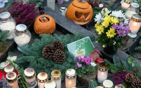 Gravdekoration med pumpor, ljus och blommor. En påminnelse om varifrån halloween kommer, med en känsla av minne och höst.
