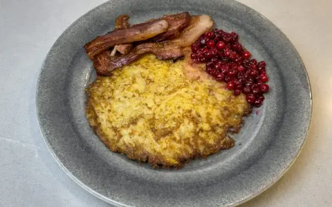 En tallrik med raggmunk, stekt fläsk och lingon. Ett klassiskt svenskt raggmunk recept som är perfekt för en mysig middag.