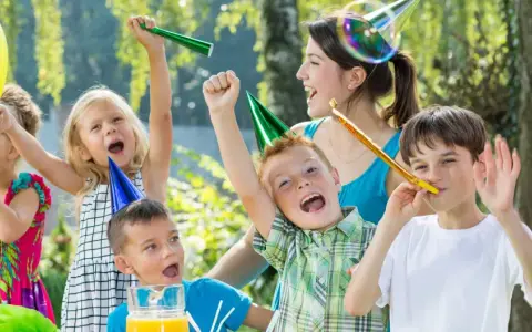 Barn firar ett 7-årskalas utomhus med ballonger, serpentiner och såpbubblor. Glada barn med partyhattar blåser i tutor.