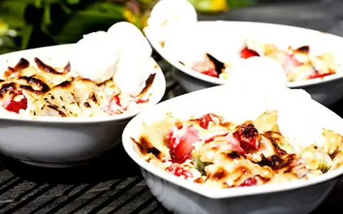 Tre skålar med varm smulpaj med jordgubbar och vaniljglass, ett perfekt Gino recept för en sommardessert.