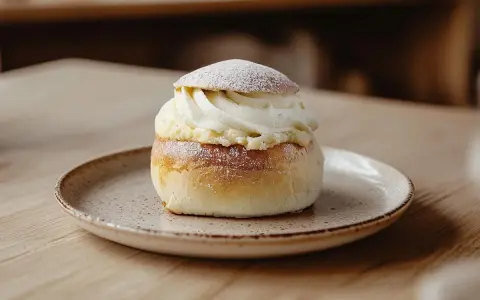 En semla med rikligt med vispad grädde och mandelmassa till semlor, pudrad med florsocker.
