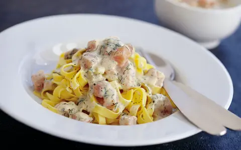 Krämig lax pasta med dill på en vit tallrik. En härlig rätt som passar perfekt för en mysig middag.