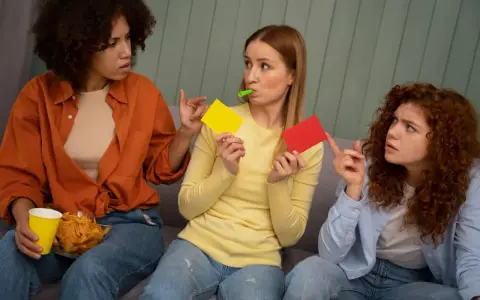 Tre vänner spelar par med en lek, en med gul och röd kort, en med chips och en med visselpipa.