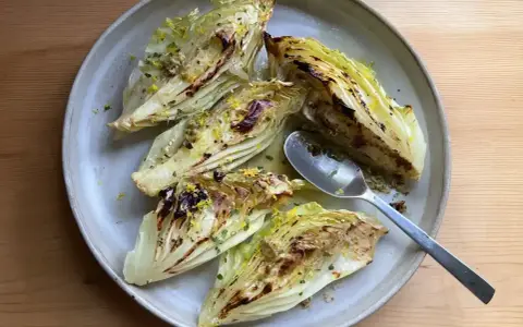 Ugnsbakad spetskål med citron och örter, serverad på en tallrik med en sked.