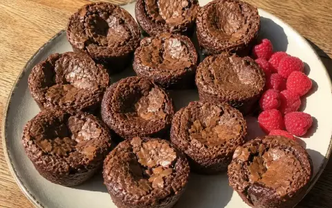 En tallrik med kladdiga chokladmuffins och färska hallon. Perfekt för fikat!
