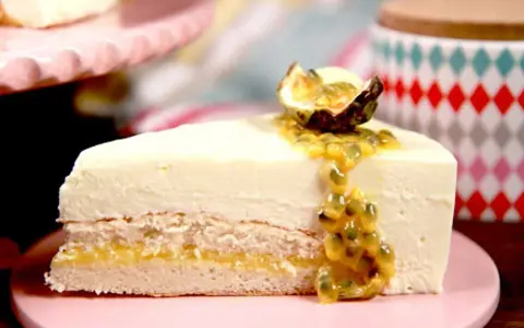 En bit tårta med len vit chokladmousse, passionsfruktssås och en halv passionsfrukt som dekoration.