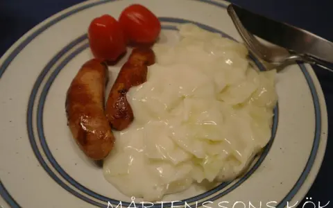 Tallrik med stuvad vitkål, två korvar och körsbärstomater. En klassisk svensk husmanskosträtt.
