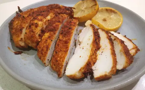Saftig kyckling i airfryer, skivad och serverad med grillade citronklyftor. Perfekt för en snabb och god middag.