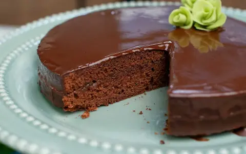 En saftig chokladkaka med blank glasyr, perfekt för ett sachertårta recept. Garnerad med gröna marsipanrosor.