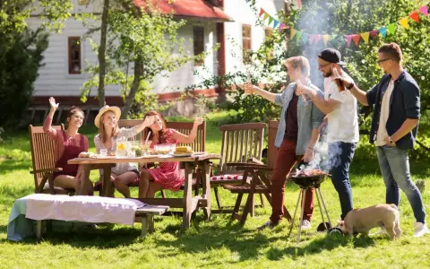Vänner njuter av grillfest och lekar till 5 kamp i trädgården. En liten gris nosar i gräset.