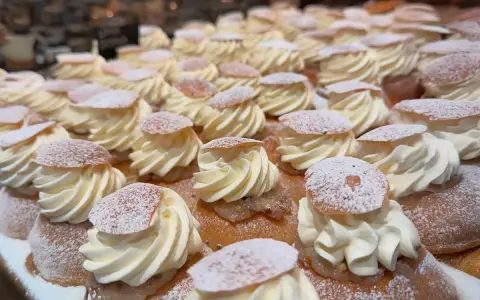 En hel hylla full med semlor, redo för semmeldagen. Krämig grädde och pudrat florsocker.