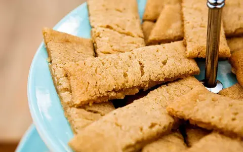 En hög med gyllene kolakakor på en ljusblå bricka. Perfekt för ett enkelt kolakakor recept.