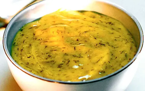 En skål med krämig gravlaxsås, perfekt för ditt gravlaxsås recept. Dill och senap syns i den gula såsen.