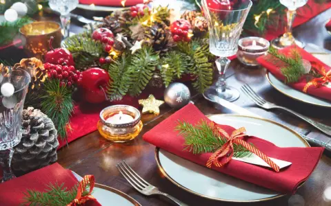 Vackert dukat julbord med röda servetter, granris, äpplen, kottar och ljus. Här ser du vad man har på ett julbord för att skapa julstämning.