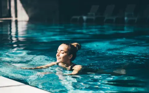 Avslappnad kvinna njuter av ett lugnt bad i en inomhuspool, en perfekt bild av spa i Sverige.