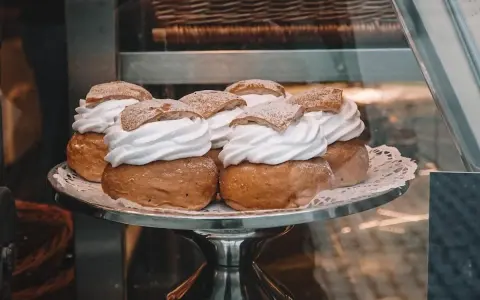 Sju semlor på ett fat, redo för pannkakans dag. Krämig grädde och pudrat socker.