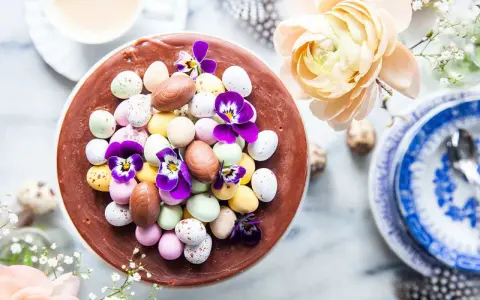 En chokladtårta dekorerad med påskägg i olika färger och violer. En perfekt påsktårta choklad för firandet.