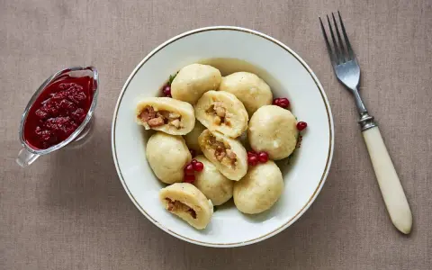 En skål med kroppkakor, en klassisk svensk rätt, serveras med lingonsylt. Recept på kroppkakor finns här.