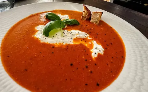 En krämig tomatsoppa med en klick gräddfil, färsk basilika och krutonger. Perfekt som en del av ett tomatsoppa recept.