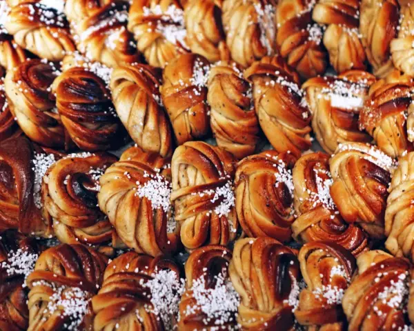En stor hög med gyllene kanelbullar, perfekta för kanelbullens dag. Strösslade med pärlsocker.
