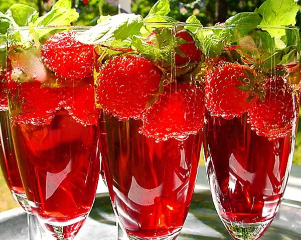 Tre glas med röd midsommar drink fyllda med jordgubbar och mynta. Bubbligt och uppfriskande.