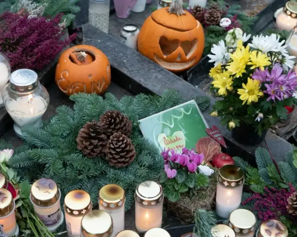 Gravdekoration med pumpor, ljus och blommor. En påminnelse om varifrån halloween kommer, med en känsla av minne och höst.