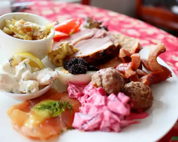 En tallrik med julbordsfavoriter: sill, köttbullar, prinskorv, ägg, rom och skinka. En perfekt checklista för julbordet!