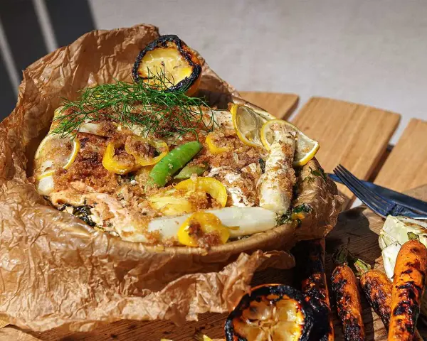En saftig fiskpaket på grillen med citron, sparris och dill. Serveras med grillade grönsaker.