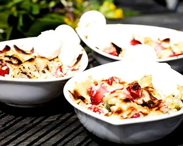 Tre skålar med varm smulpaj med jordgubbar och vaniljglass, ett perfekt Gino recept för en sommardessert.
