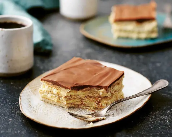 En bit vanilj bakelser med chokladglasyr på en tallrik, redo att avnjutas med en kopp kaffe.