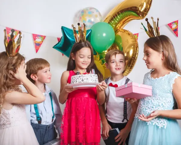 Barn med kronor firar födelsedag med tårta och presenter. Perfekt för barnkalas lekar 6 år.