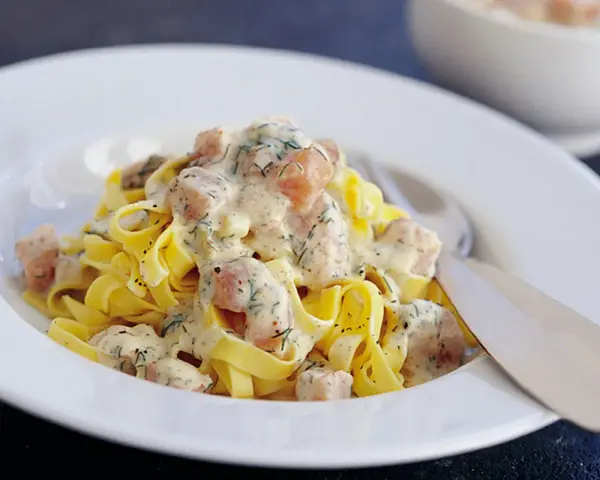 Krämig lax pasta med dill på en vit tallrik. En härlig rätt som passar perfekt för en mysig middag.
