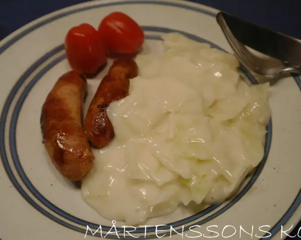 Tallrik med stuvad vitkål, två korvar och körsbärstomater. En klassisk svensk husmanskosträtt.
