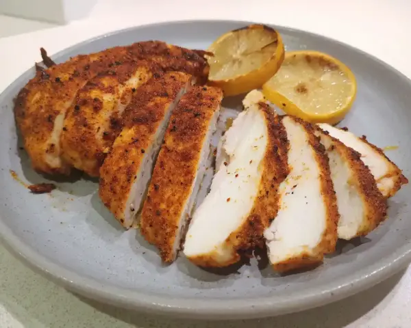 Saftig kyckling i airfryer, skivad och serverad med grillade citronklyftor. Perfekt för en snabb och god middag.