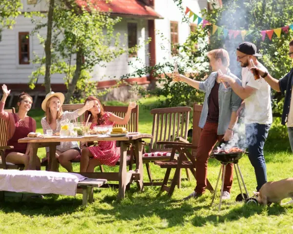 Vänner njuter av grillfest och lekar till 5 kamp i trädgården. En liten gris nosar i gräset.