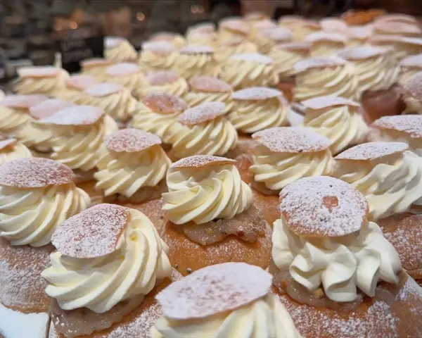 En hel hylla full med semlor, redo för semmeldagen. Krämig grädde och pudrat florsocker.