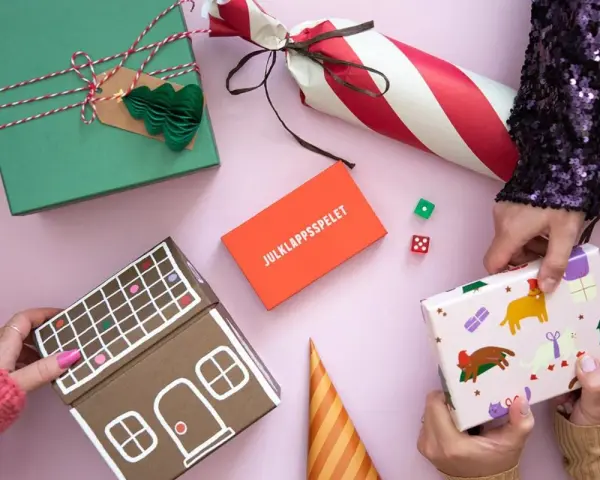 Julklappsleken är igång! Presenter, tärningar och en pepparkakshus-liknande låda ligger redo för att bytas.