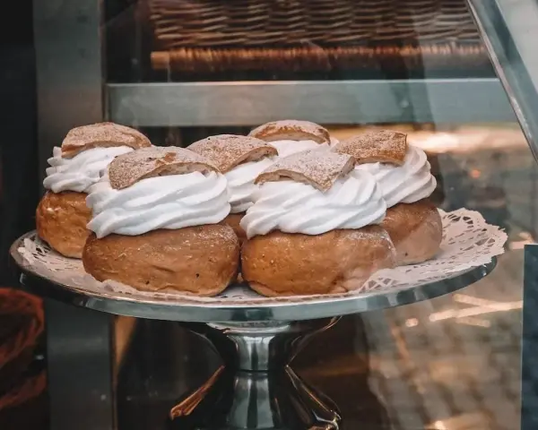 Sju semlor på ett fat, redo för pannkakans dag. Krämig grädde och pudrat socker.