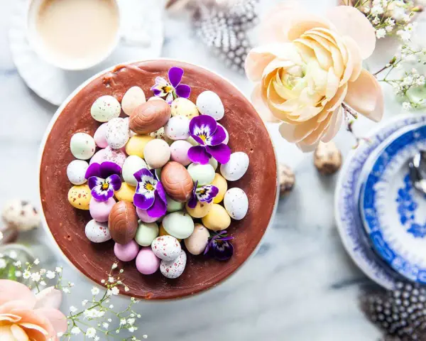 En chokladtårta dekorerad med påskägg i olika färger och violer. En perfekt påsktårta choklad för firandet.
