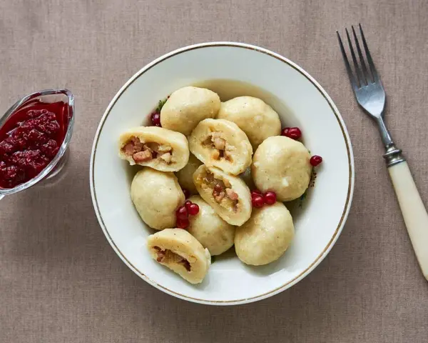 En skål med kroppkakor, en klassisk svensk rätt, serveras med lingonsylt. Recept på kroppkakor finns här.