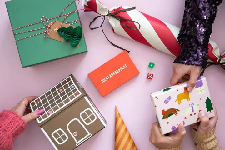 Julklappsleken är igång! Presenter, tärningar och en pepparkakshus-liknande låda ligger redo för att bytas.