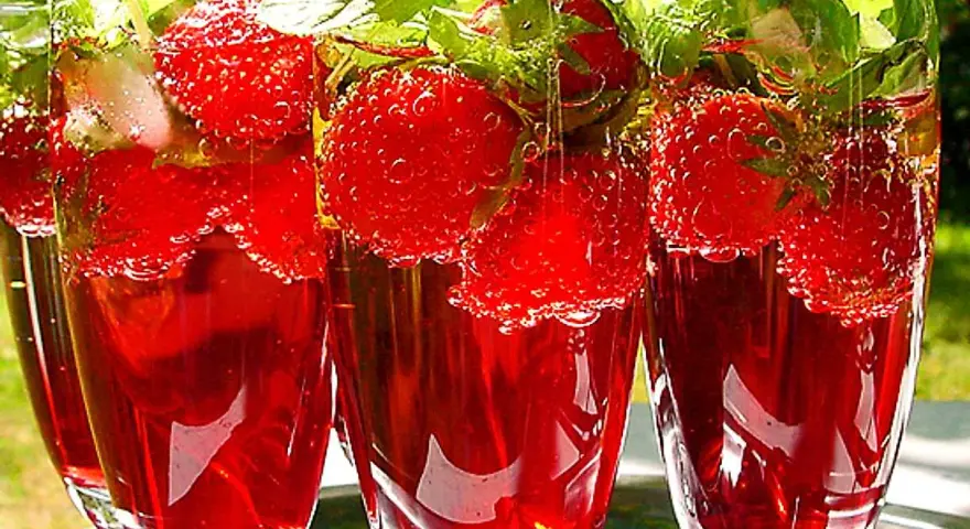 Tre glas med röd midsommar drink fyllda med jordgubbar och mynta. Bubbligt och uppfriskande.