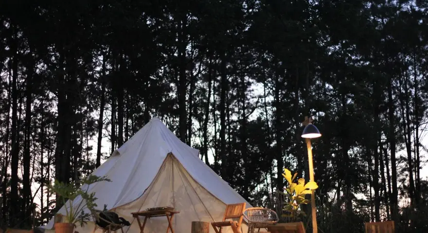 En vit glampingtält står redo för äventyr i en svensk skog. Mysigt och naturnära glamping i Sverige.