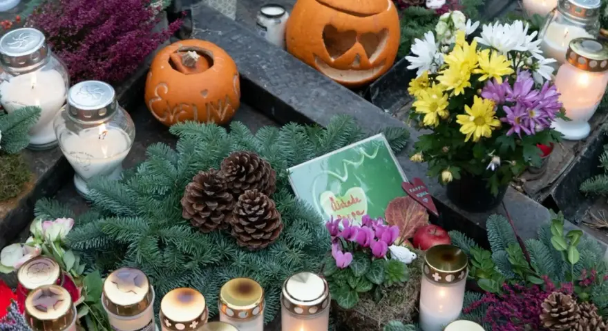 Gravdekoration med pumpor, ljus och blommor. En påminnelse om varifrån halloween kommer, med en känsla av minne och höst.