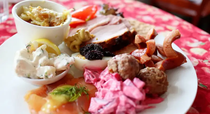 En tallrik med julbordsfavoriter: sill, köttbullar, prinskorv, ägg, rom och skinka. En perfekt checklista för julbordet!