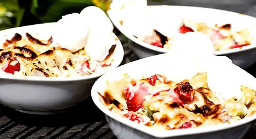Tre skålar med varm smulpaj med jordgubbar och vaniljglass, ett perfekt Gino recept för en sommardessert.