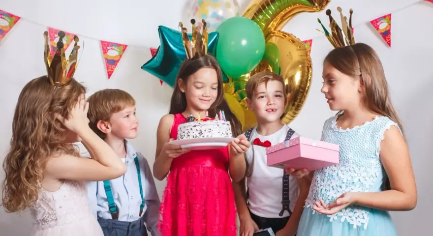 Barn med kronor firar födelsedag med tårta och presenter. Perfekt för barnkalas lekar 6 år.
