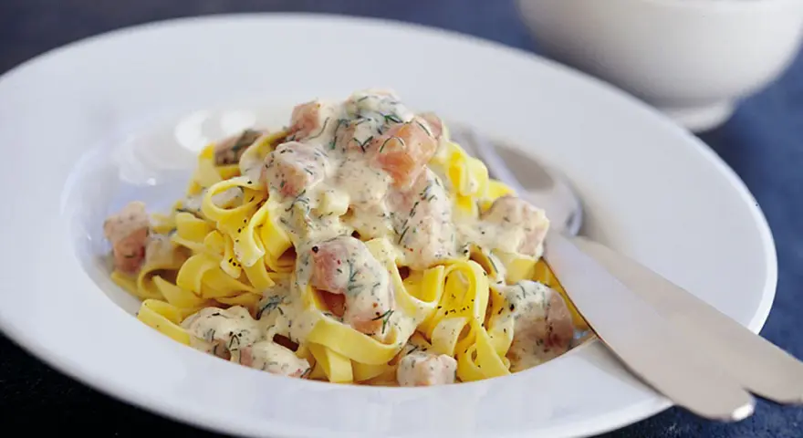 Krämig lax pasta med dill på en vit tallrik. En härlig rätt som passar perfekt för en mysig middag.