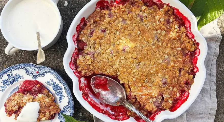 En härlig hallonpaj smulpaj med krispig topping, serverad med vaniljsås. Perfekt sommarfika!