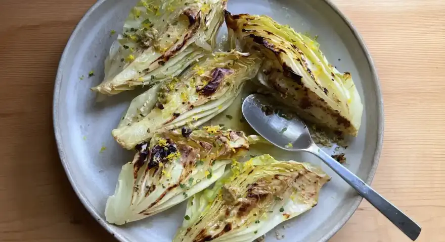 Ugnsbakad spetskål med citron och örter, serverad på en tallrik med en sked.